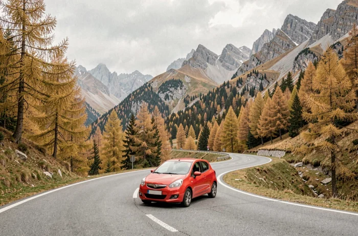 Compacte rouge sur une route sinueuse des Alpes françaises entourée de mélèzes dorés en automne
